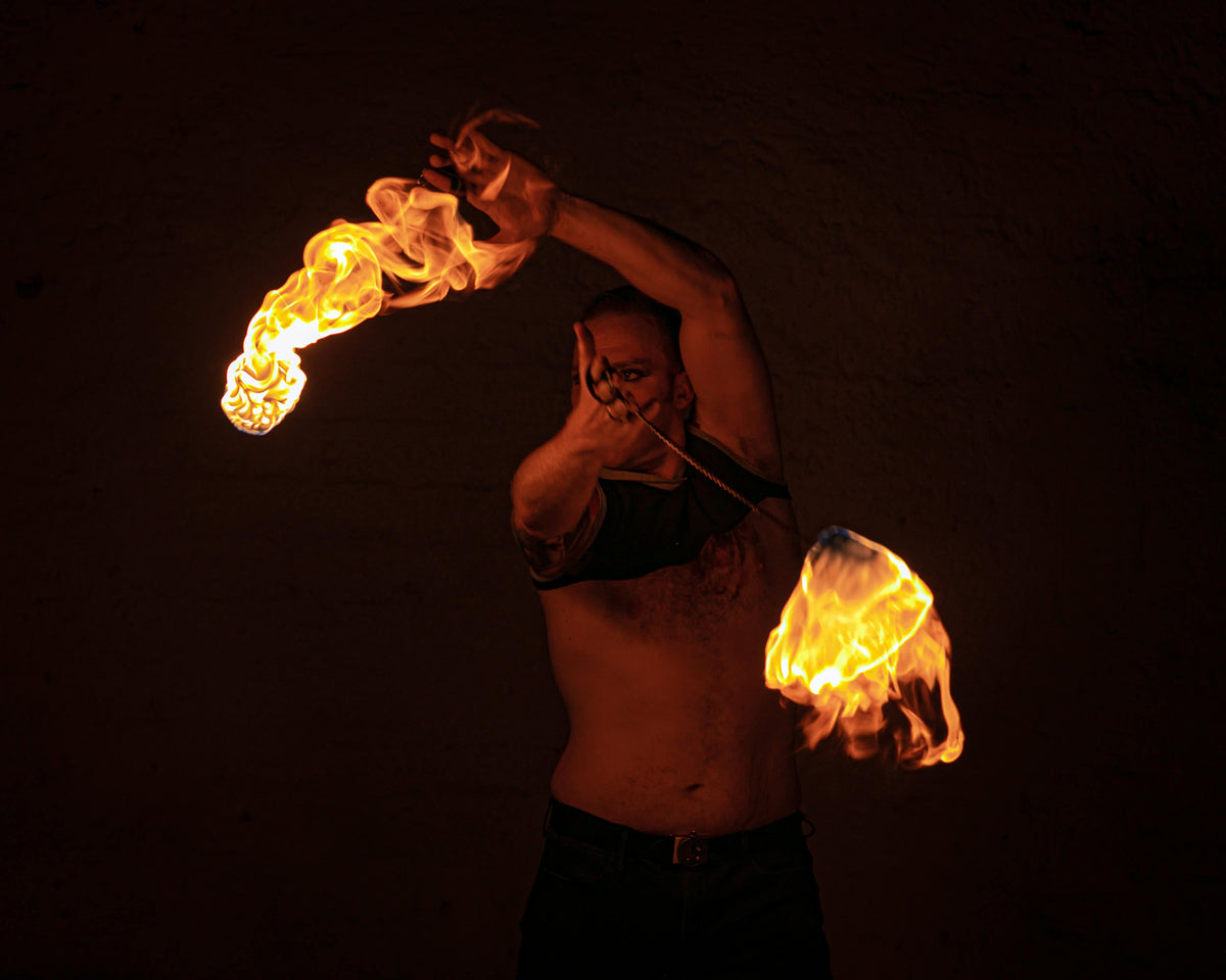 Fire poi set with two flaming tips on chains in an overhead pose