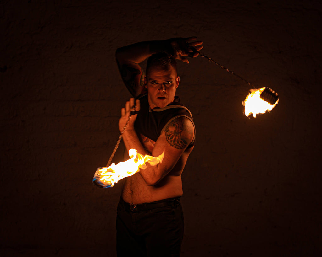 Fire poi set with flaming tips on chains held by performer