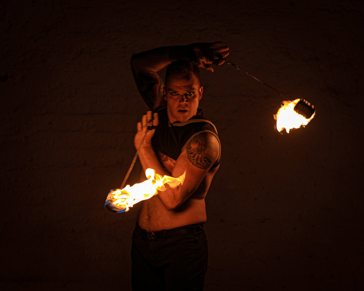 Fire poi set with flaming tips on chains held by performer