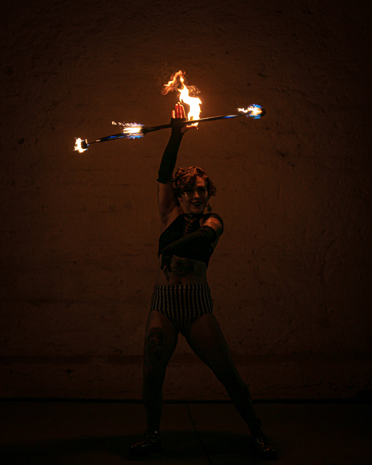 Fire hoop with burning wicks on a ring, performer holding prop overhead.