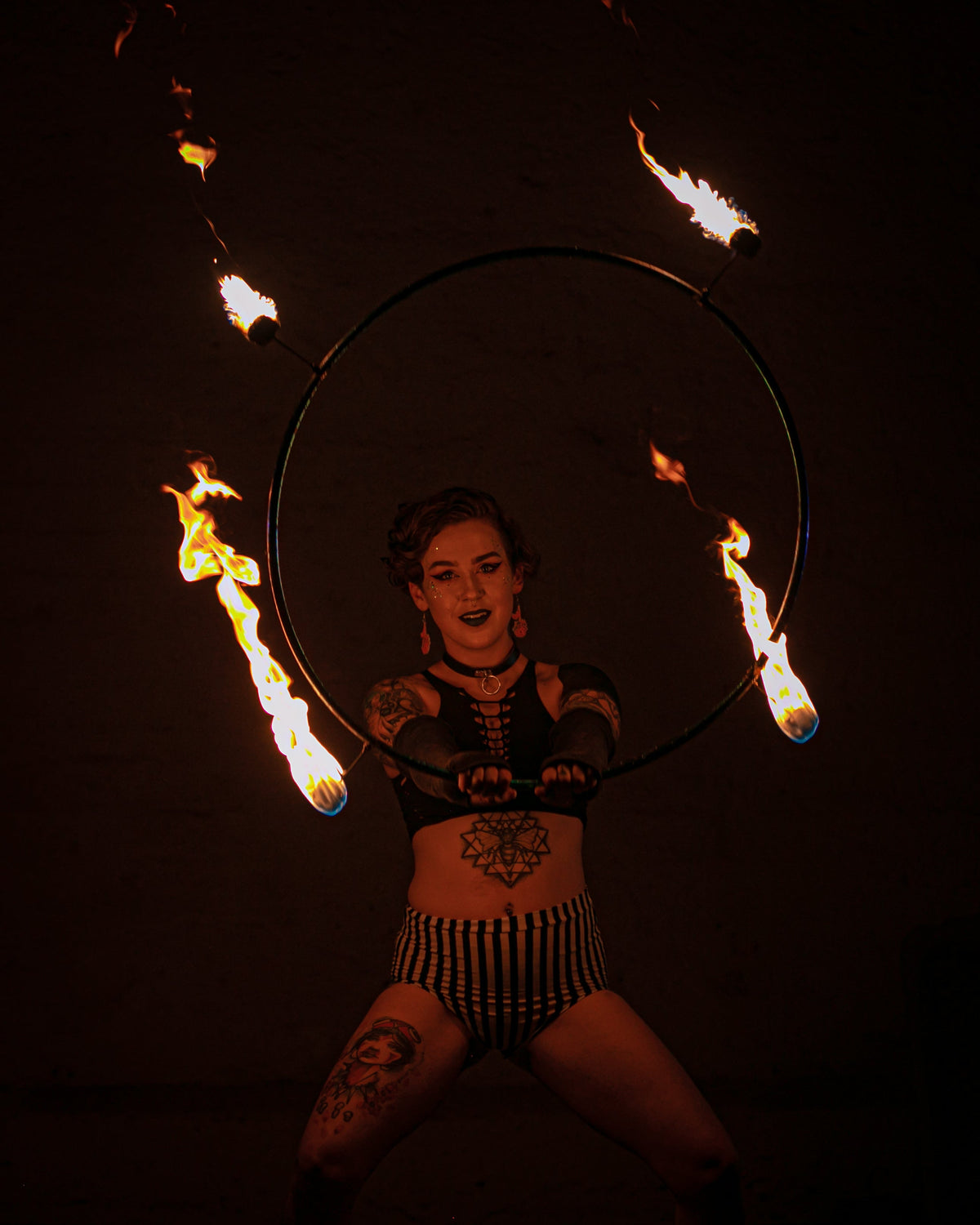 Fire hoop ring with burning wicks, held by performer.