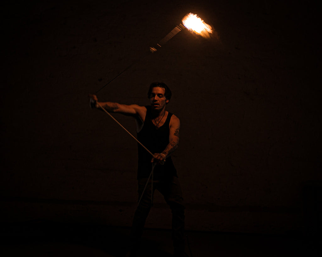 Rope dart fire mid-swing with burning flame head attached to rope