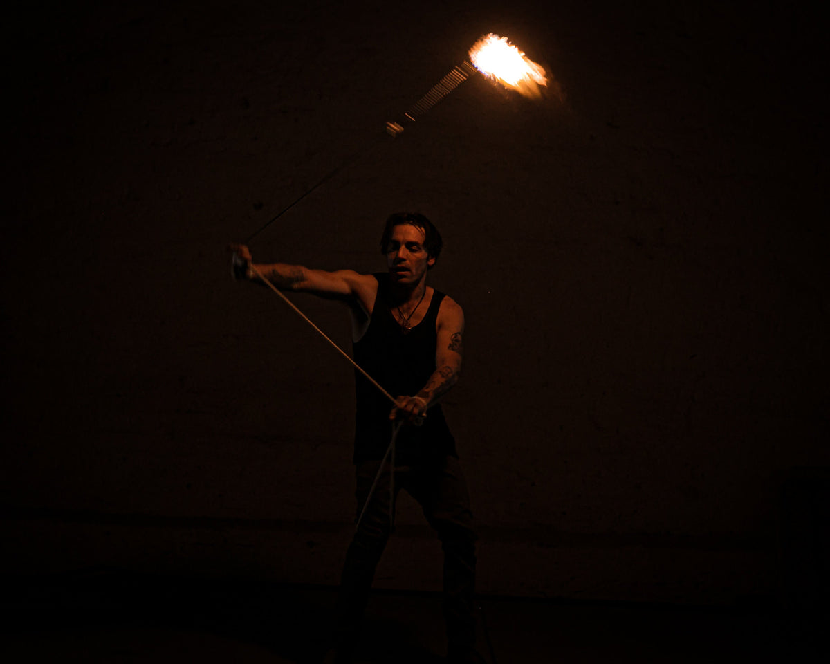 Rope dart fire mid-swing with burning flame head attached to rope