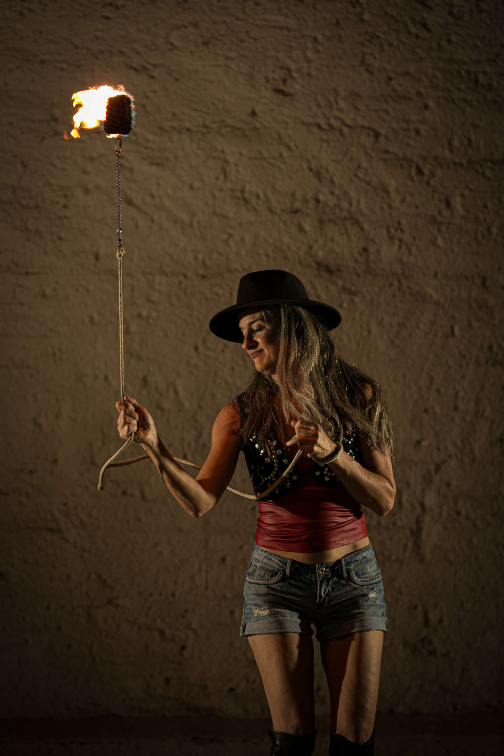Rope dart fire held by performer, burning flame head on rope leash