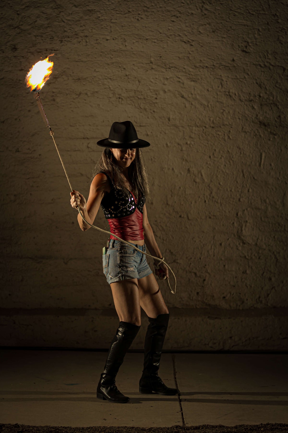 Rope dart fire performer holding a burning flame head on a rope leash