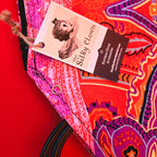 Paisley fan cover corner with looped black cord and a fabric tag attached.