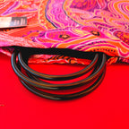 Folded fan cover fabric with bright paisley print and black ring stays across opening.