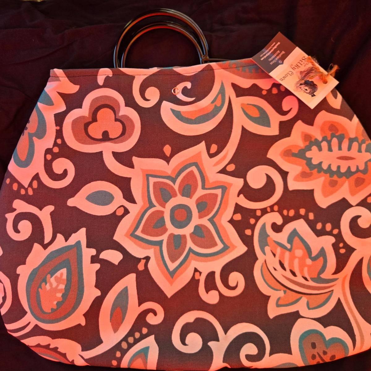 Pink and orange floral-pattern fan cover pouch with black cord ties and hanging tags.