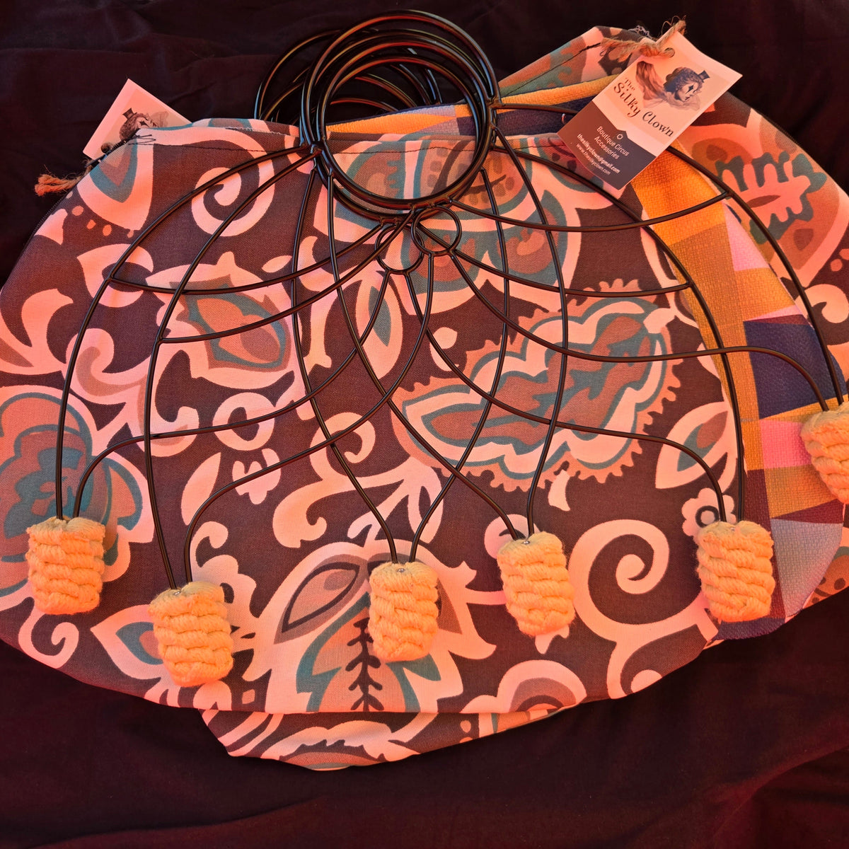 Patterned fan cover with black ring stays and orange pom-pom tassels along the hem.