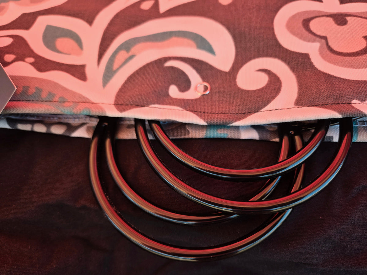 Maroon fan cover with pink swirls and scalloped cutout showing black ring stays.